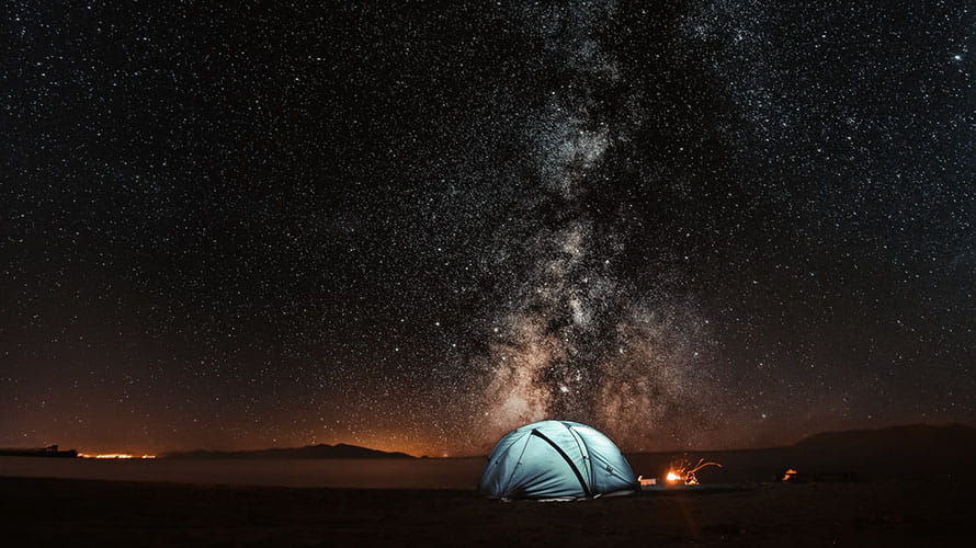 The milky way visible above a beach and a tent