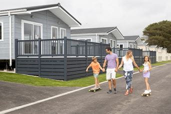 A family walking past a row of luxury lodges on a holiday park in Cornwall