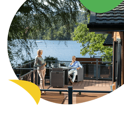 A couple relaxing on their lodge veranda overlooking a lake