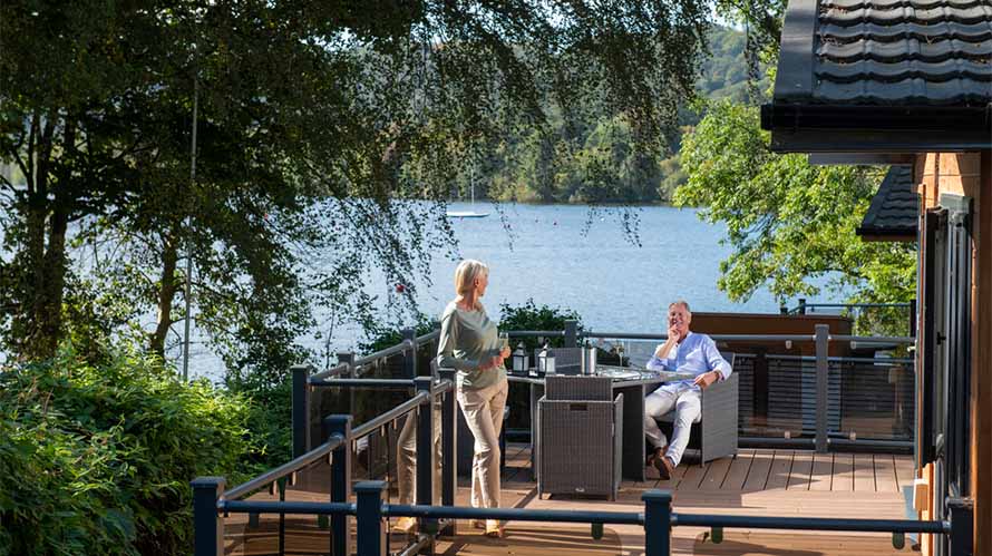 A couple relaxing on their lodge veranda in the Lake District
