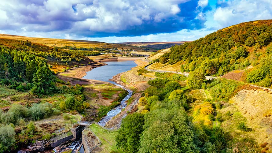A golden landscape of trees changing colour for autumn, overlooking a reservoir in Yorkshire