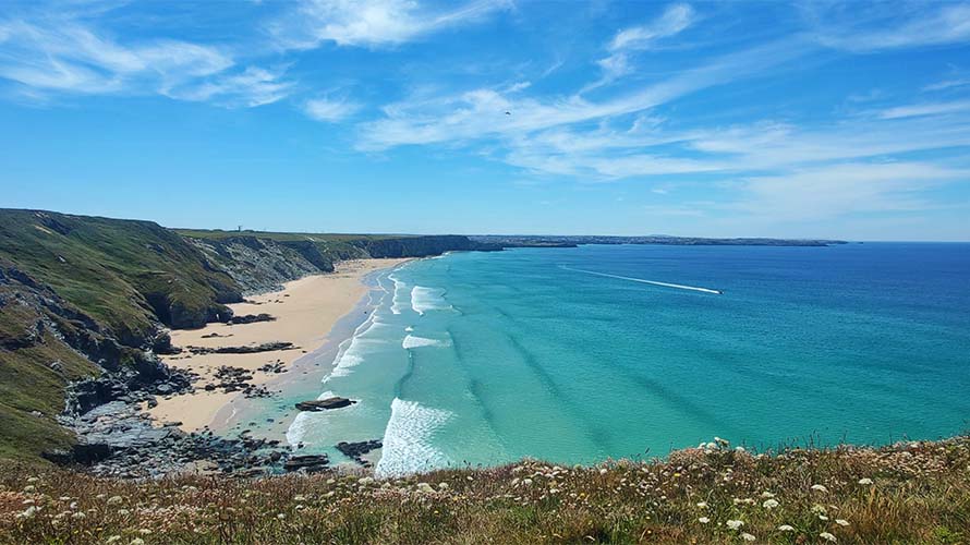 Gentle waves rolling into Watergate Bay in Cornwall on a sunny summer day