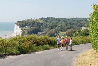 A family walking along a coastal path overlooking the white cliffs of Dover