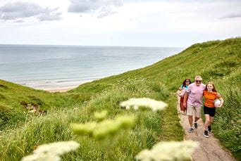 A family walking along a grassy coastal path