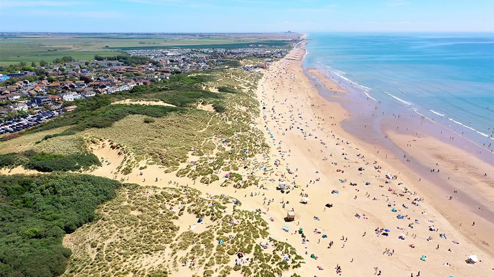 An aerial view over Camber Sands Beach, busy with holidaymakers on the sand
