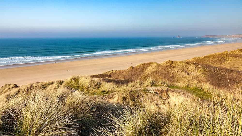 A view over the grassy dunes and sands of Gwithian Towans in Cornwall