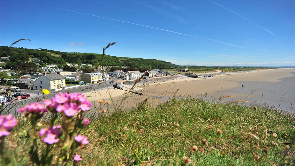A green hilltop overlooking Pendine Sands town and beach