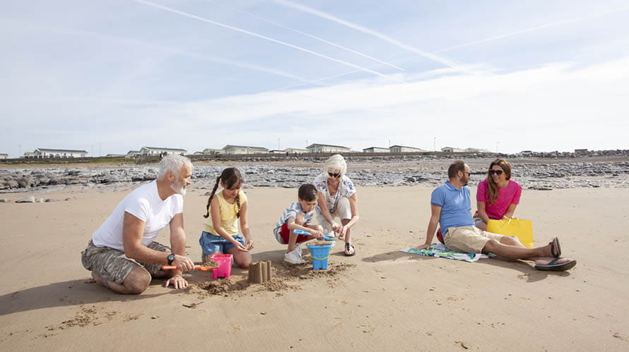 A family relaxing and building sandcastles on the beach at Trecco Bay