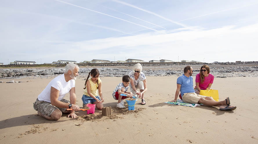 A family relaxing and building sandcastles on the beach at Trecco Bay