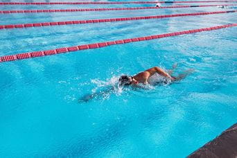 A man swimming lengths in an outdoor swimming pool