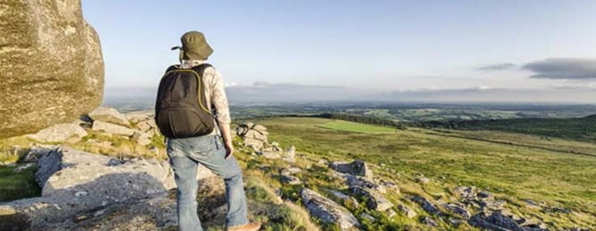 A walker wearing a rucksack enjoying a view of the countryside