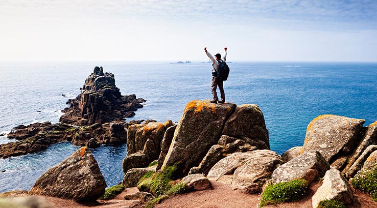 Man standing on rocks at Lands End in Cornwall
