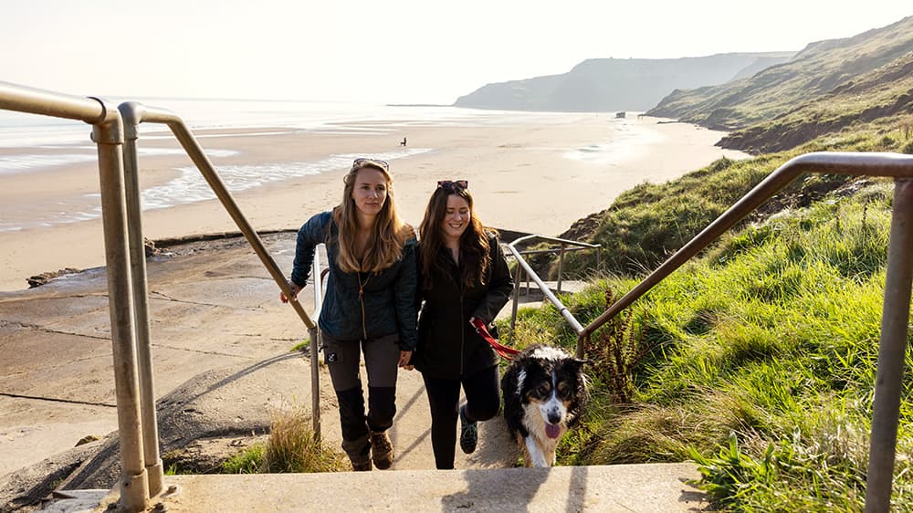 Two girls walking off the beach with their dog