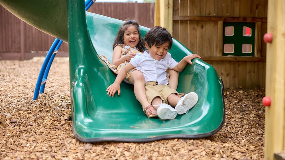 Two children on a slide in a playground