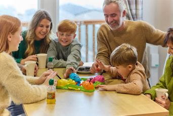 A family playing a board game inside their holiday caravan on a rainy day