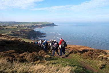 Walkers hiking along Cleveland Way, with views over the Yorkshire coast