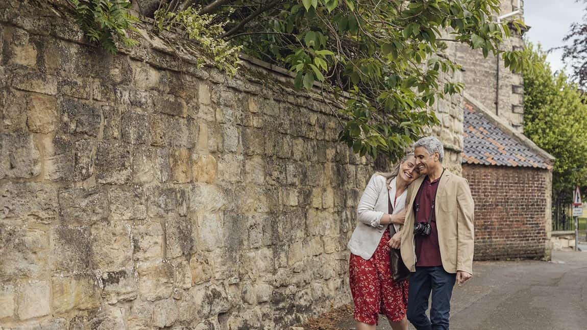 A couple walking alongside the walls of a stone castle