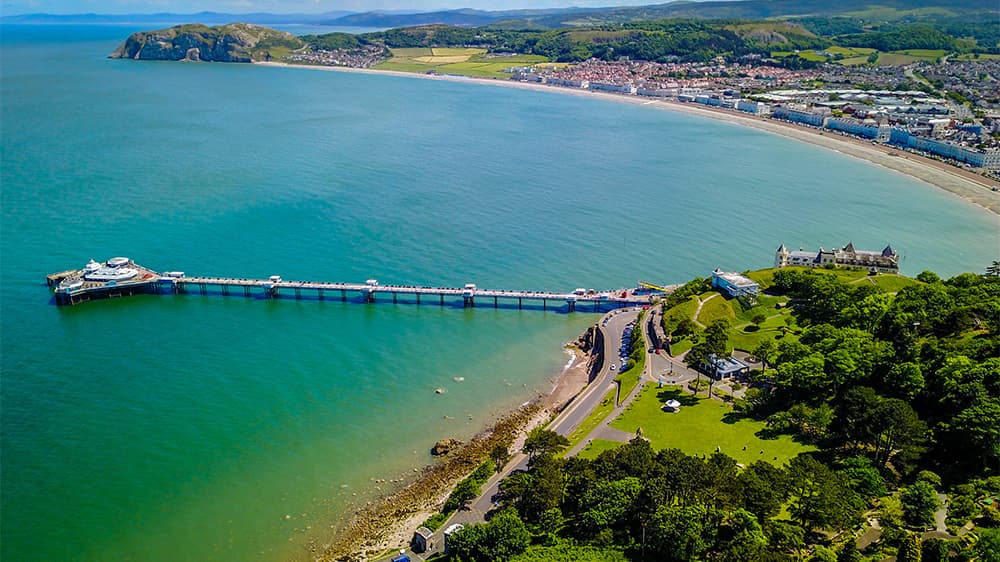 An aerial view over a bay and pier in Llandudno