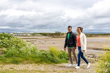 A couple walking along the beach by Ocean Edge Holiday Park