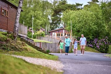 A family walking past luxury lodges at Warmwell Holiday Park
