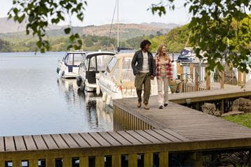 A couple walking along the jetty at White Cross Bay Holiday Park, overlooking Windermere