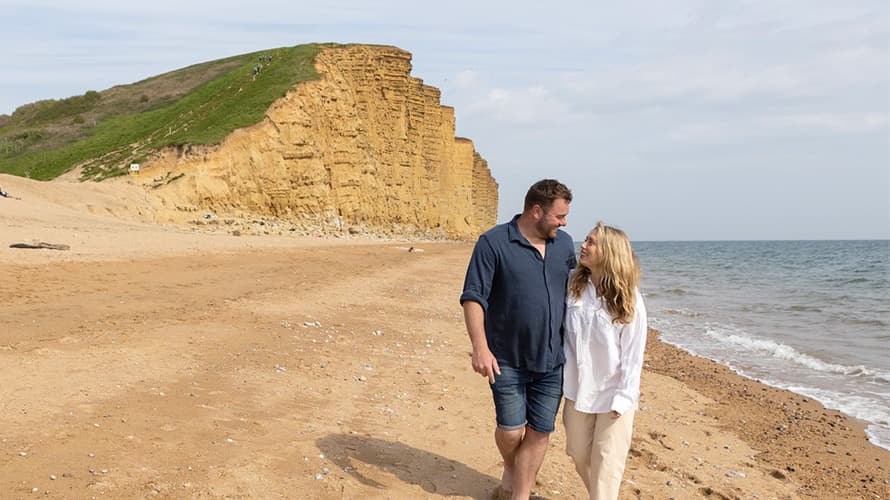 A couple taking a romantic stroll on the beach near some cliffs