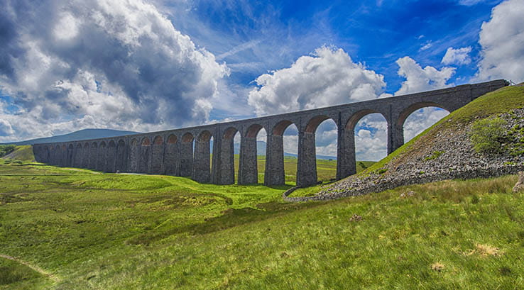 A historic railway viaduct bridge crossing a green valley