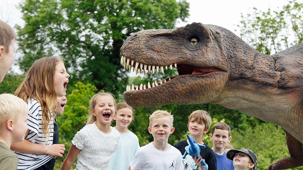 Kids excitedly gathered around a model dinosaur