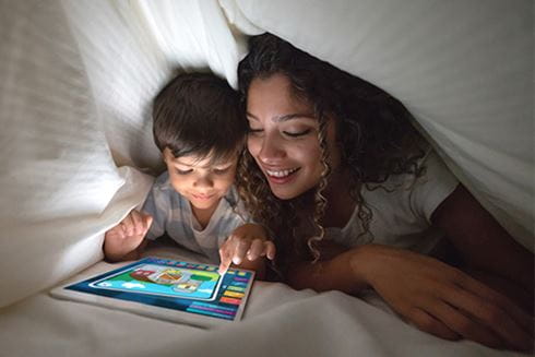 A mother and sun browsing a tablet in bed