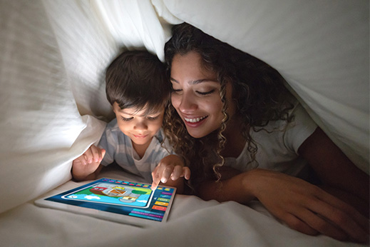 A mother and sun browsing a tablet in bed