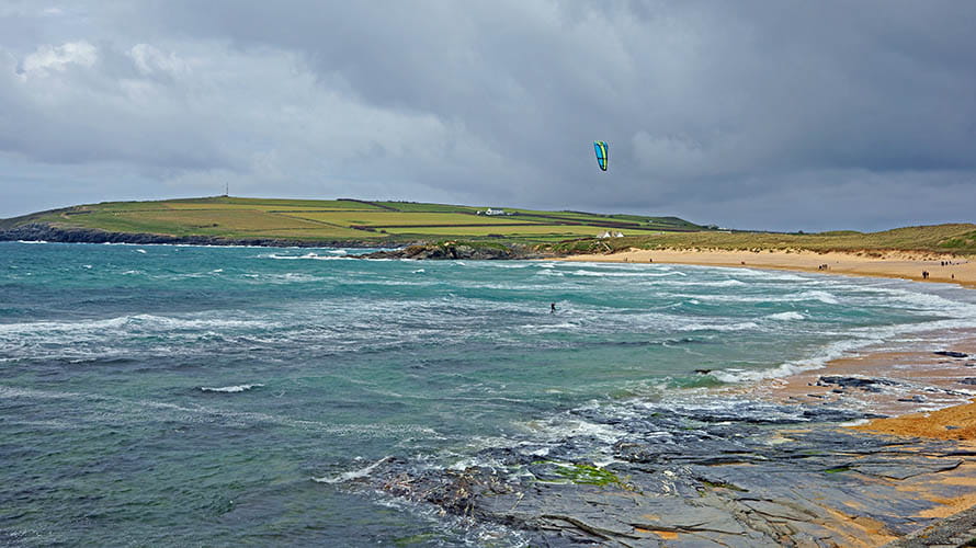 A kite surfer at Constantine Bay Beach, with Trevose Head Lighthouse visible behind