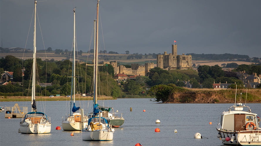 Boats in Amble Harbour with Warkworth Castle in the background
