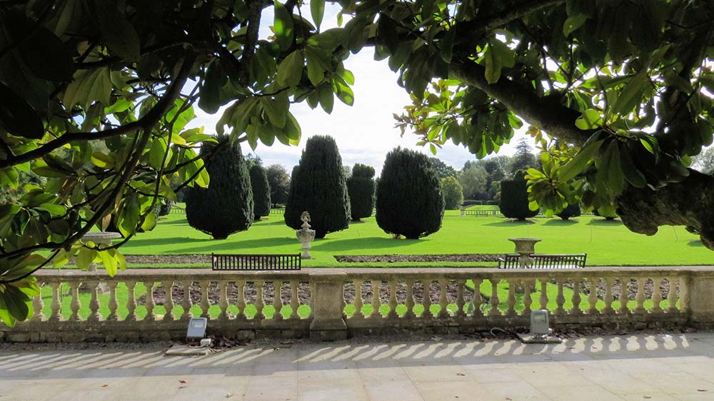 A stone terrace overlooking a formal garden with ornamental bushes 