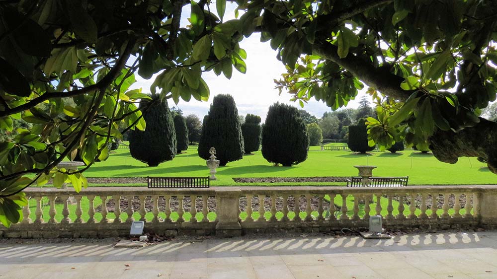 A stone terrace overlooking a formal garden with ornamental bushes
