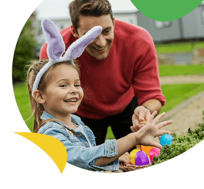 A dad and his daughter hunting for Easter eggs on a holiday park