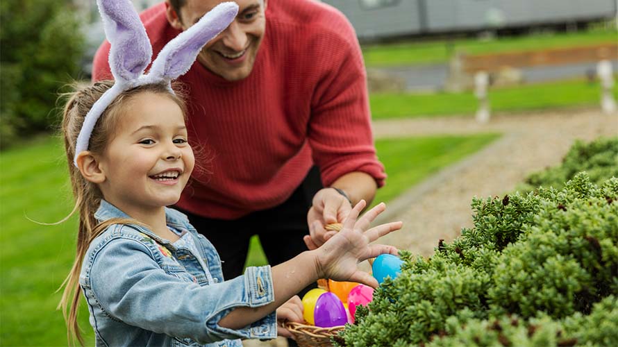 A girl and her father hunting for Easter eggs on a caravan park