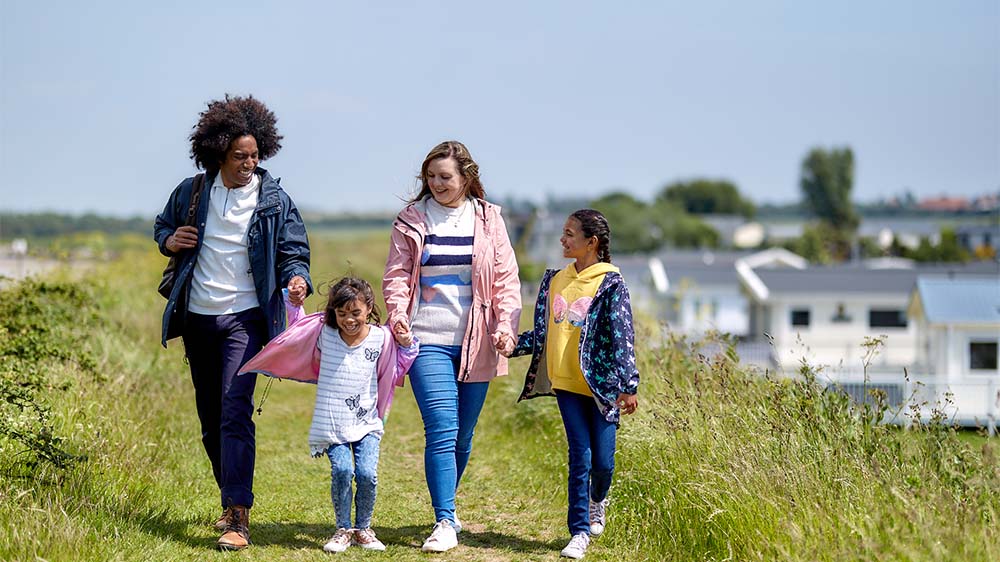 A family walking along a grassy path next to a holiday park in Essex