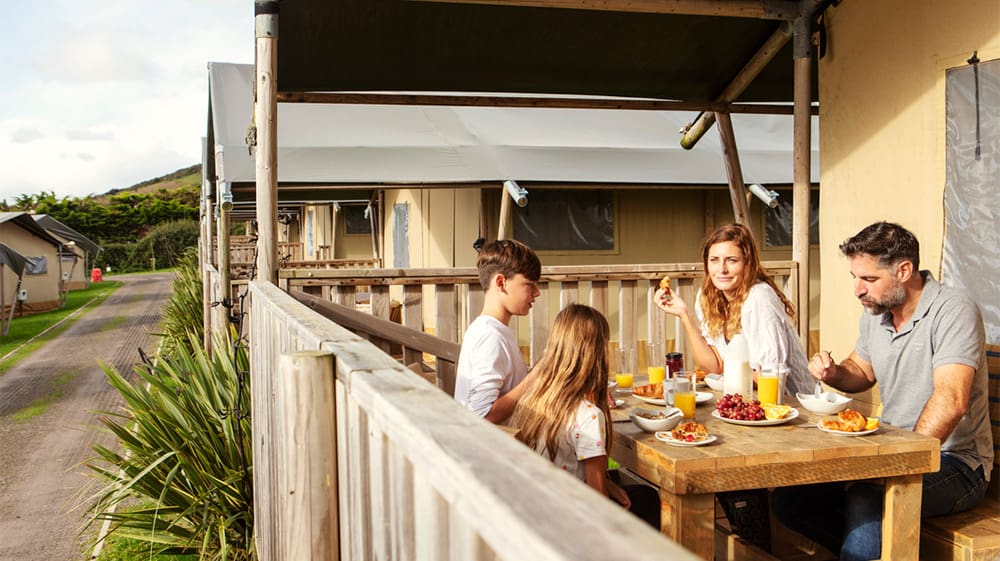 A family having lunch on the veranda of their glamping tent