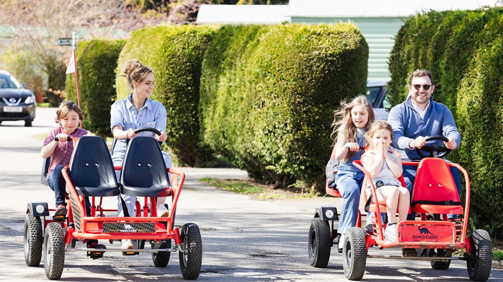 A family riding two pedal karts around a holiday park