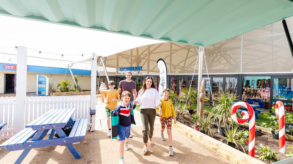 A family walking past the Pavilion at Trecco Bay Holiday Park