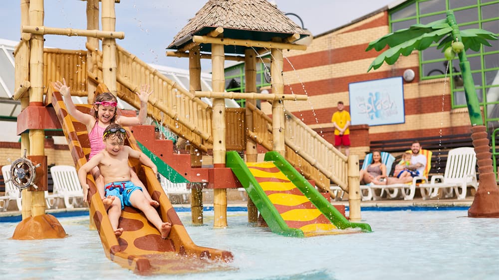 Kids going down the water slide in the outdoor splash zone at Vauxhall Holiday Park