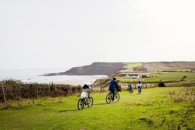 A family cycling along the coast