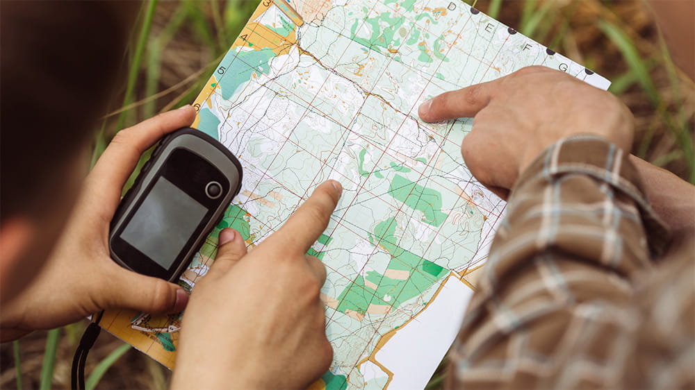 Friends taking part in geocaching looking at a map to find coordinates