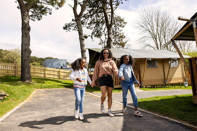 Teenagers walking past a glamping tent