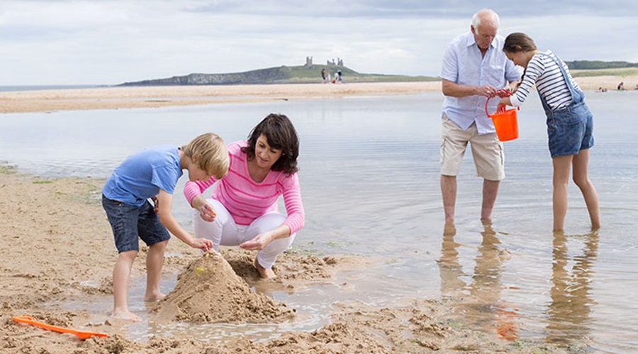 Grandparents playing in sand with grandchildren