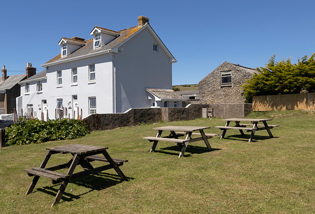 The garden and picnic benches outside Lundy House cottage at Ruda Holiday Park in Devon
