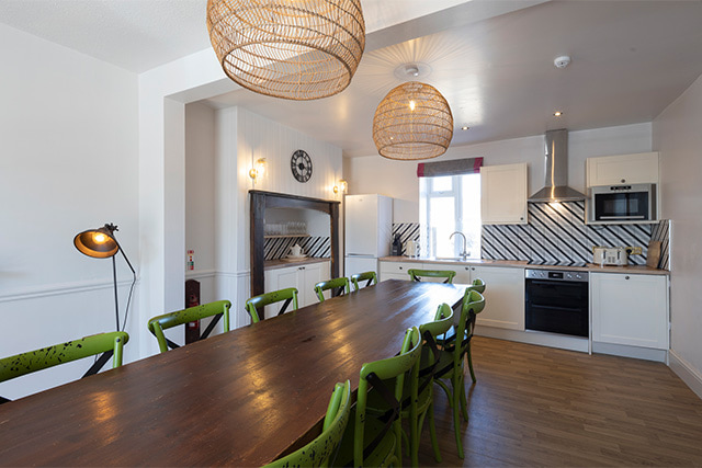 A dining table and kitchen at Lundy House in Ruda Holiday Park