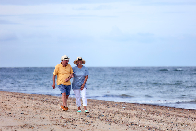 A retired couple enjoying a walk on a sandy beach
