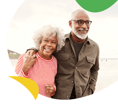 A retired couple walking down the beach smiling