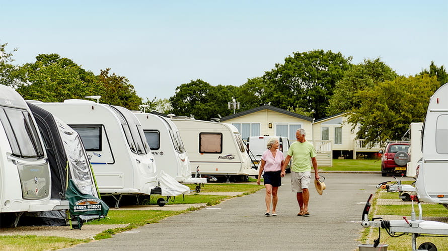 A retired couple walking through a touring caravan campsite